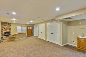 Unfurnished living room featuring carpet flooring, a stone fireplace, and sink