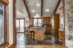 Kitchen with beamed ceiling, light stone counters, a wealth of natural light, and built in fridge