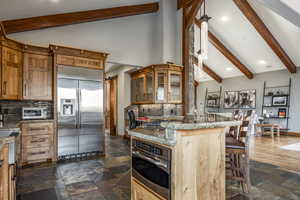 Kitchen featuring decorative backsplash, a breakfast bar, stainless steel appliances, beam ceiling, and a center island