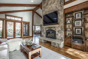 Living room featuring beam ceiling, a fireplace, high vaulted ceiling, and light hardwood / wood-style floors