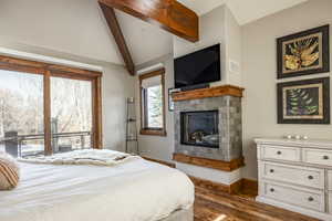 Bedroom with vaulted ceiling with beams, a fireplace, and dark wood-type flooring