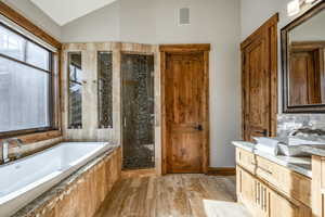 Bathroom with vanity, plus walk in shower, lofted ceiling, and hardwood / wood-style flooring