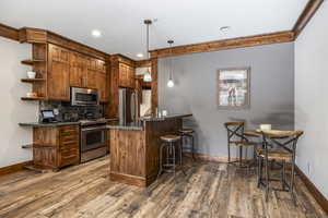 Kitchen with hardwood / wood-style flooring, a kitchen bar, stainless steel appliances, and hanging light fixtures