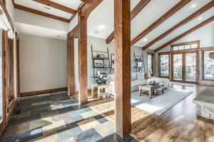 Unfurnished living room with dark hardwood / wood-style floors, lofted ceiling with beams, and french doors