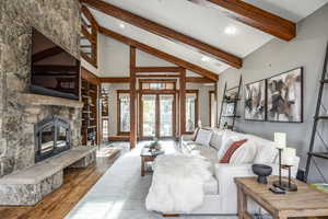 Living room featuring high vaulted ceiling, french doors, a fireplace, beamed ceiling, and wood-type flooring