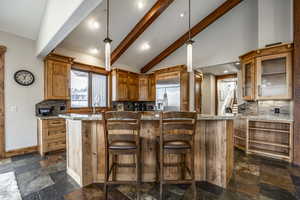 Kitchen featuring decorative backsplash, light stone countertops, stainless steel built in fridge, and beamed ceiling