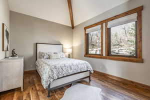 Bedroom featuring vaulted ceiling with beams and dark hardwood / wood-style floors