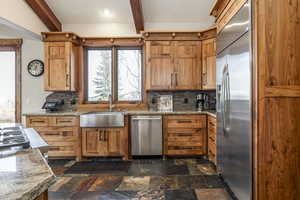 Kitchen with light stone countertops, sink, stainless steel appliances, beamed ceiling, and decorative backsplash