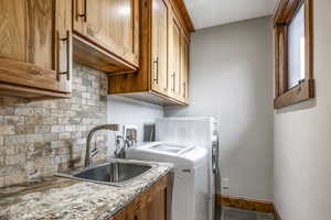 Clothes washing area with cabinets, washing machine and dryer, and sink