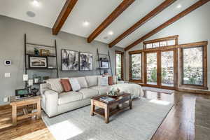 Living room featuring beam ceiling, light wood-type flooring, high vaulted ceiling, and french doors