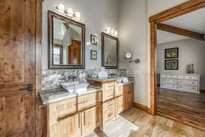 Bathroom featuring hardwood / wood-style flooring, vanity, and backsplash