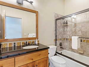 Full bathroom with vanity, toilet, and shower / bath combination with glass door