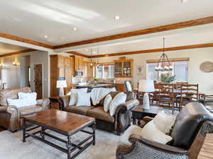 Living room featuring beamed ceiling, a notable chandelier, and crown molding