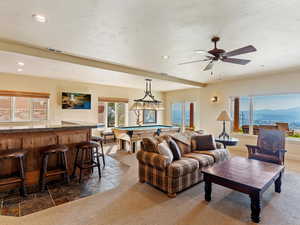 Living room featuring ceiling fan, dark colored carpet, billiards, a mountain view, and bar