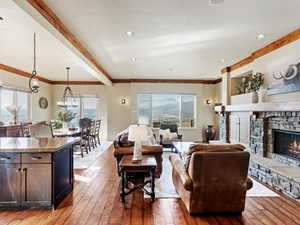 Living room with beamed ceiling, hardwood / wood-style floors, a chandelier, a fireplace, and ornamental molding