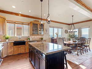 Kitchen featuring backsplash, an inviting chandelier, hanging light fixtures, light hardwood / wood-style flooring, and a kitchen island