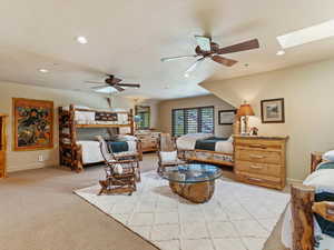 Bedroom with a skylight, light carpet, and ceiling fan