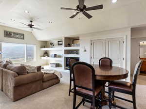 Carpeted dining area featuring ceiling fan and vaulted ceiling