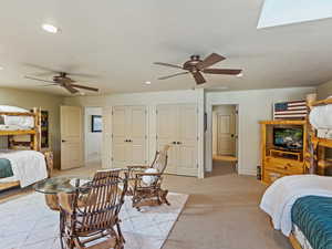 Carpeted bedroom with a skylight and ceiling fan