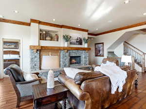 Living room with hardwood / wood-style flooring, ornamental molding, and a fireplace