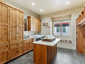 Laundry area with cabinets, dark tile patterned floors, sink, and washing machine and clothes dryer