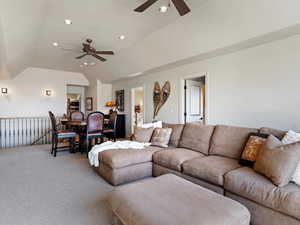 Living room with carpet, ceiling fan, and lofted ceiling