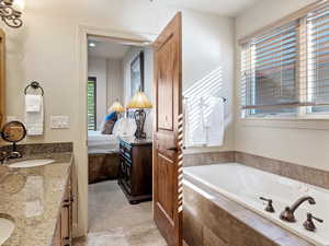 Bathroom featuring tiled tub and vanity