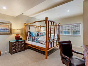 Bedroom with beam ceiling and light colored carpet