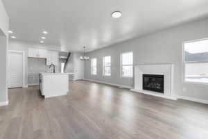 Unfurnished living room featuring sink, a chandelier, and light hardwood / wood-style floors