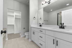 Bathroom with toilet, vanity, tile patterned flooring, and walk in shower