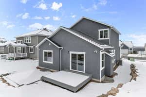 Snow covered rear of property featuring covered porch and cooling unit