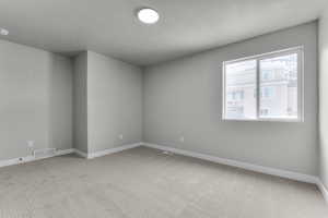 Carpeted spare room featuring a textured ceiling