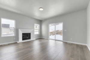 Unfurnished living room featuring a textured ceiling and hardwood / wood-style floors