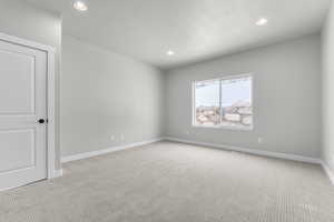 Unfurnished room with a textured ceiling and light colored carpet