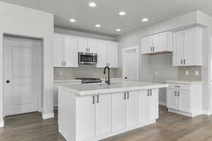 Kitchen with white cabinets, stainless steel appliances, a kitchen island with sink, and sink