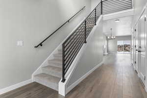 Stairway with hardwood / wood-style flooring and a notable chandelier