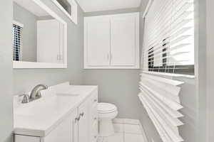 Bathroom with toilet, vanity, and tile patterned floors