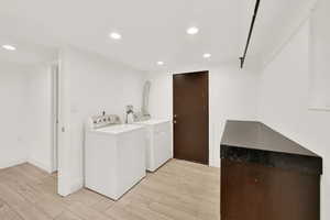 Laundry area with light wood-type flooring and independent washer and dryer