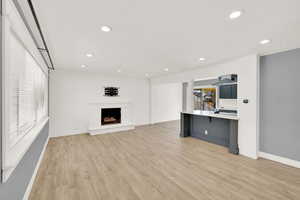 Unfurnished living room featuring light wood-type flooring and a fireplace