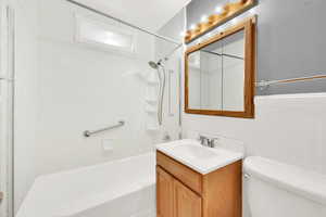 Full bathroom with toilet, tiled shower / bath combo, and vanity