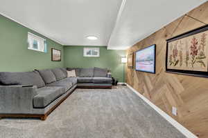 Carpeted living room with crown molding and wooden walls