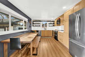 Kitchen with appliances with stainless steel finishes, backsplash, light hardwood / wood-style flooring, and light brown cabinetry