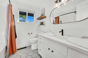 Full bathroom with tile patterned flooring, vanity, toilet, and shower / bath combo with shower curtain