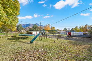 View of jungle gym featuring a mountain view, a yard, and a trampoline