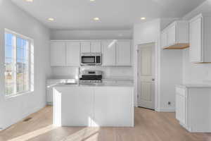 Kitchen featuring white cabinetry, a center island with sink, light hardwood / wood-style flooring, and appliances with stainless steel finishes