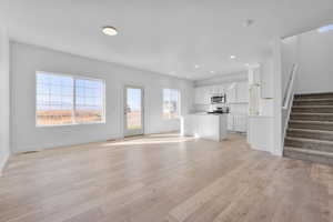 Unfurnished living room with plenty of natural light, light hardwood / wood-style floors, and sink