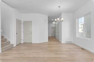 Spare room with a chandelier and light hardwood / wood-style floors