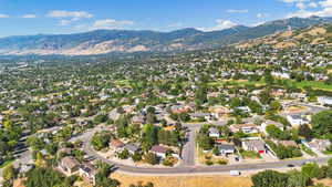 Aerial view of property and surrounding area featuring nearby suburban area and a mountain backdrop