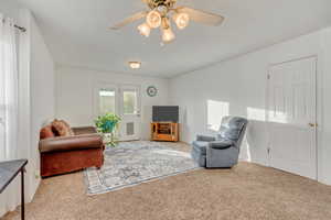 Living room with carpet flooring and ceiling fan