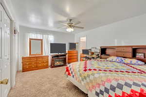 Bedroom featuring a textured ceiling, carpet floors, a closet, and ceiling fan